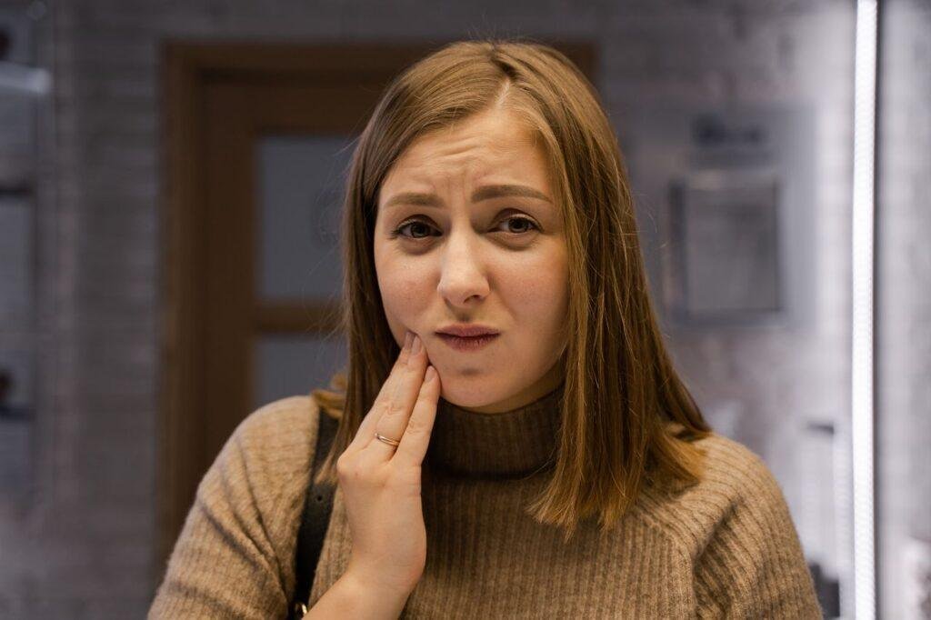 Woman holding her cheek after a dental injury in Richmond Hill