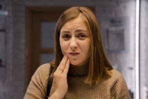Woman holding her cheek after a dental injury in Richmond Hill
