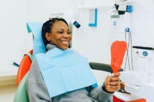 Woman checking her gum line in a mirror during a dental visit in Richmond Hill