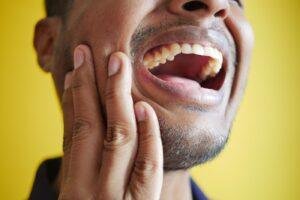 Man holding his cheek with tooth pain caused by stress