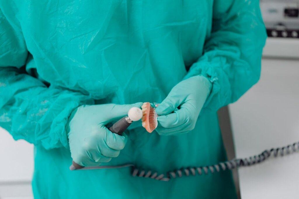 Dental professional adjusting and polishing a denture to relieve pressure