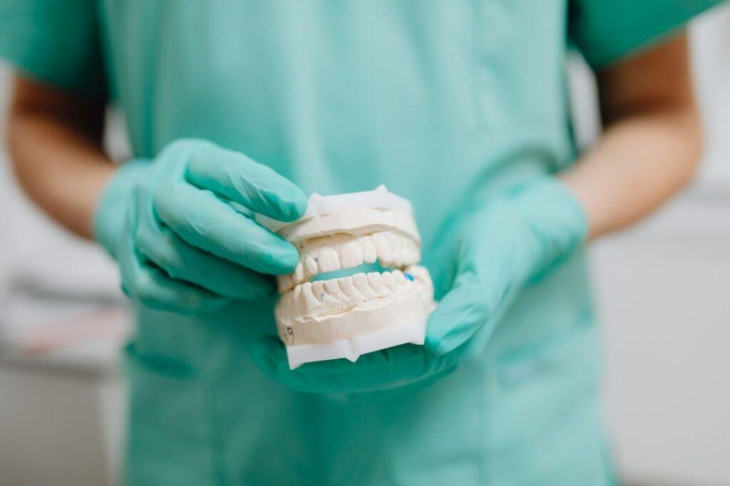 Dental professional examining a denture cast to assess fit problems