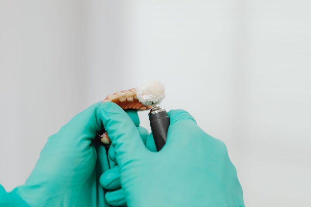 Dental professional repairing a denture with specialized tools