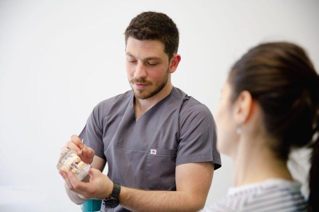 Dentist explaining a dental implant model during a consultation