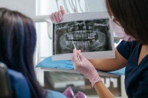 Dentist showing a patient a dental x-ray on a screen