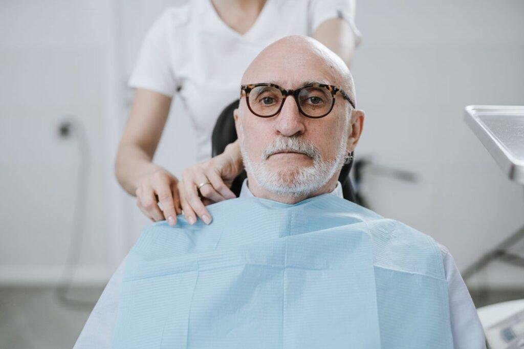 Elderly man in a dental chair during a denture fit assessment