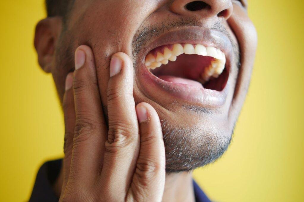 Man holding his cheek with tooth pain needing an emergency dentist