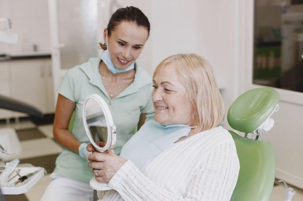 Smiling senior woman checking the fit of her dentures in a mirror