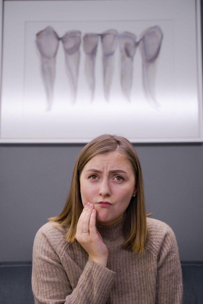 Woman holding her cheek because of a sore inside her mouth